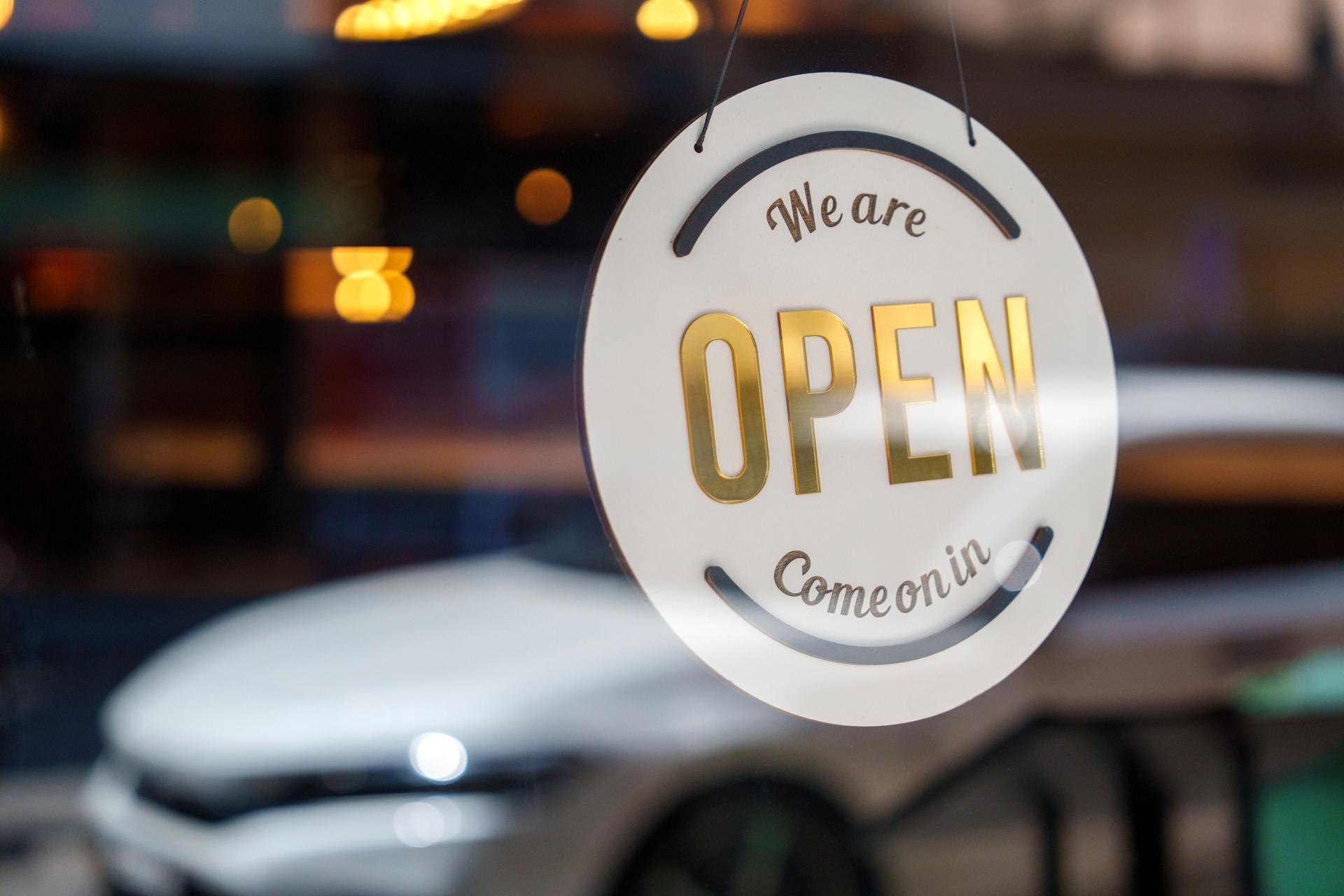 An open sign on a modern restaurant hangs on the door at the entrance, representing food and drink establishment and small business concept